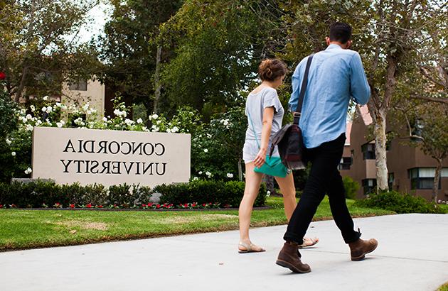 两个学生正走过康考迪亚大学的标志