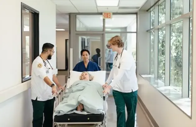 Nursing students moving patient in hospital bed down the hall